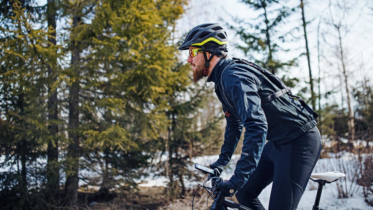 Cyclist Rides Bike Down Forest Path In Warm Clothing