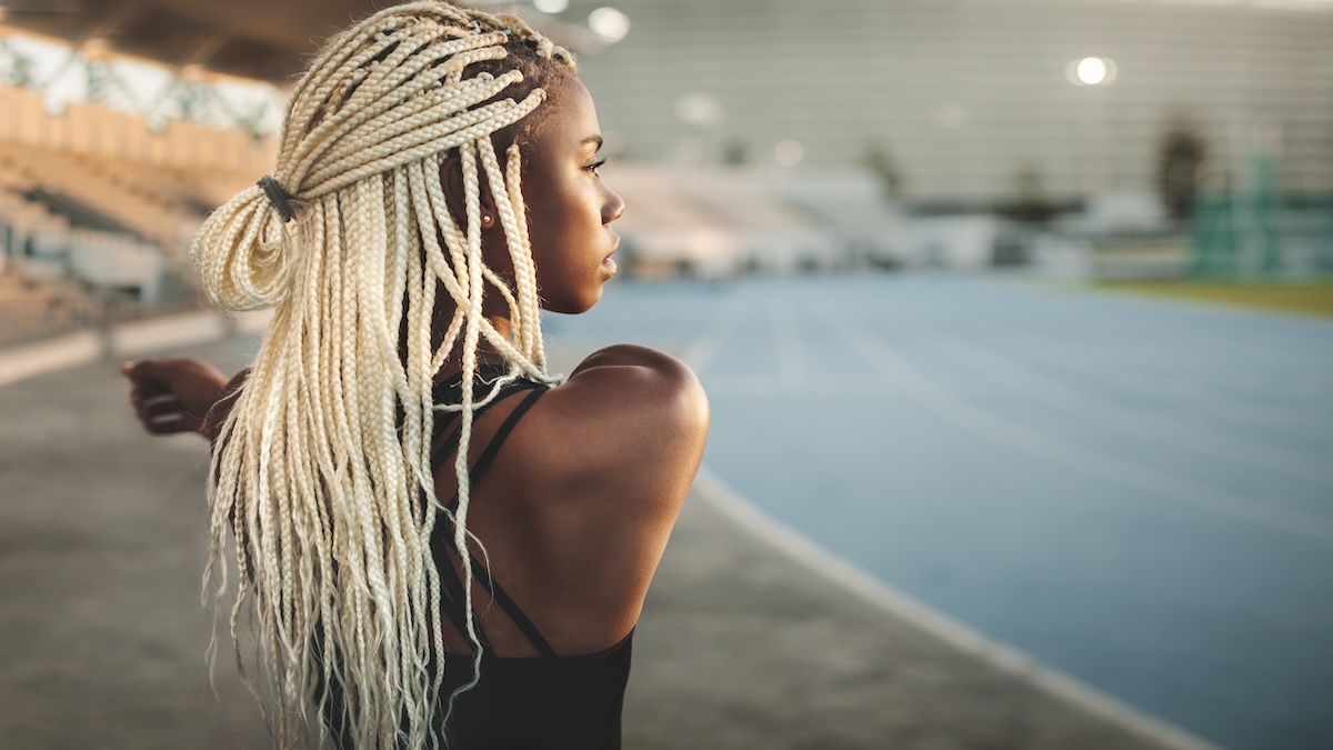 Female Track Athlete Looks Across Mentally Preparing While Stretching Her Arm