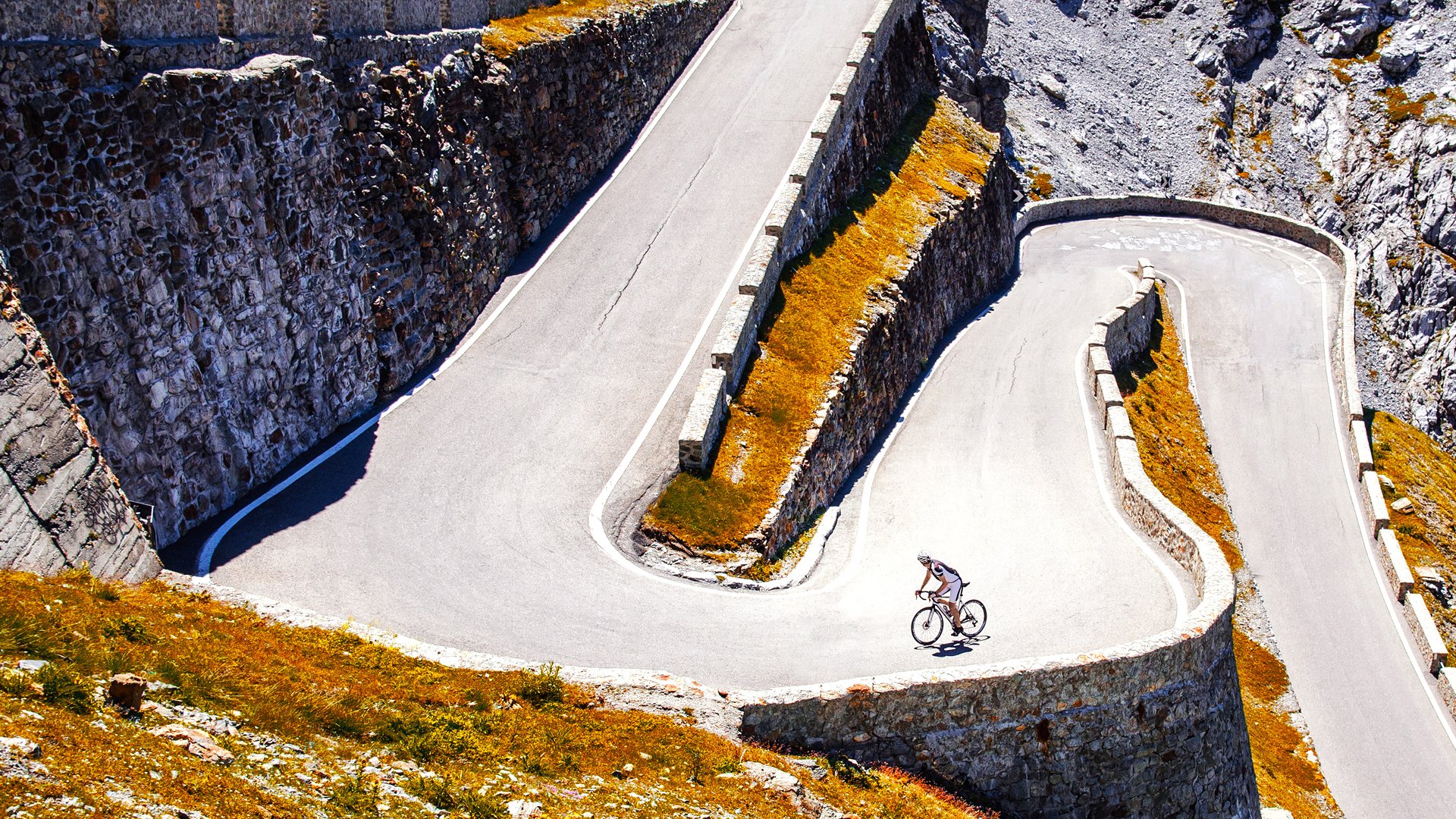 Image Of A Cyclist Riding Up A Steep Mountain Pass On Switchbacks